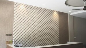 Una zona de recepción con un papel tapiz estampado, un mostrador de recepción y una lámpara en el techo.