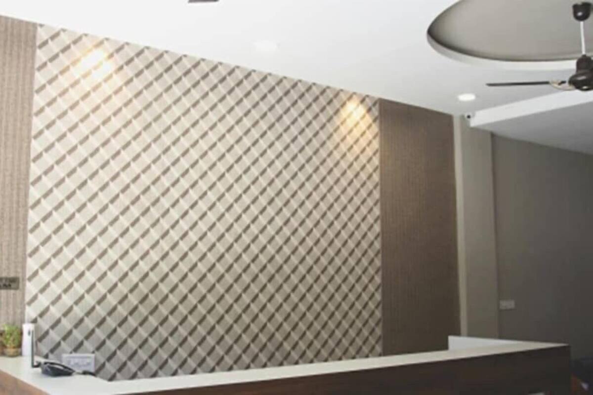 A reception area with a patterned wall, a reception desk, and a ceiling light fixture.