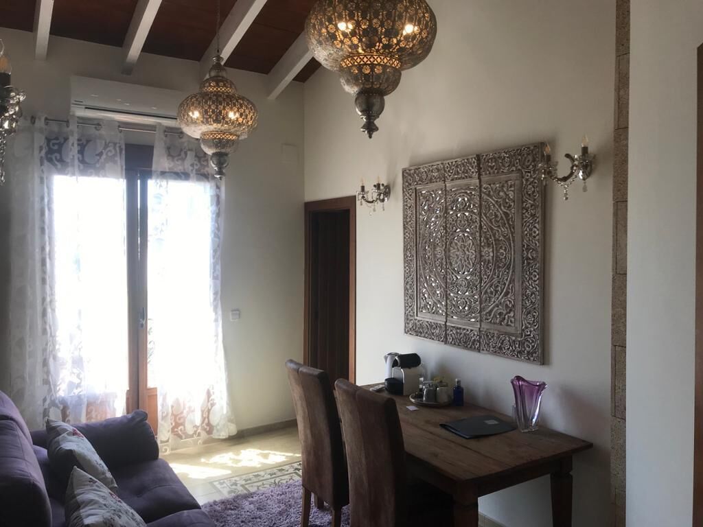 Un salón acogedor con una mesa de comedor de madera, sofá púrpura y detalles decorativos en las paredes.