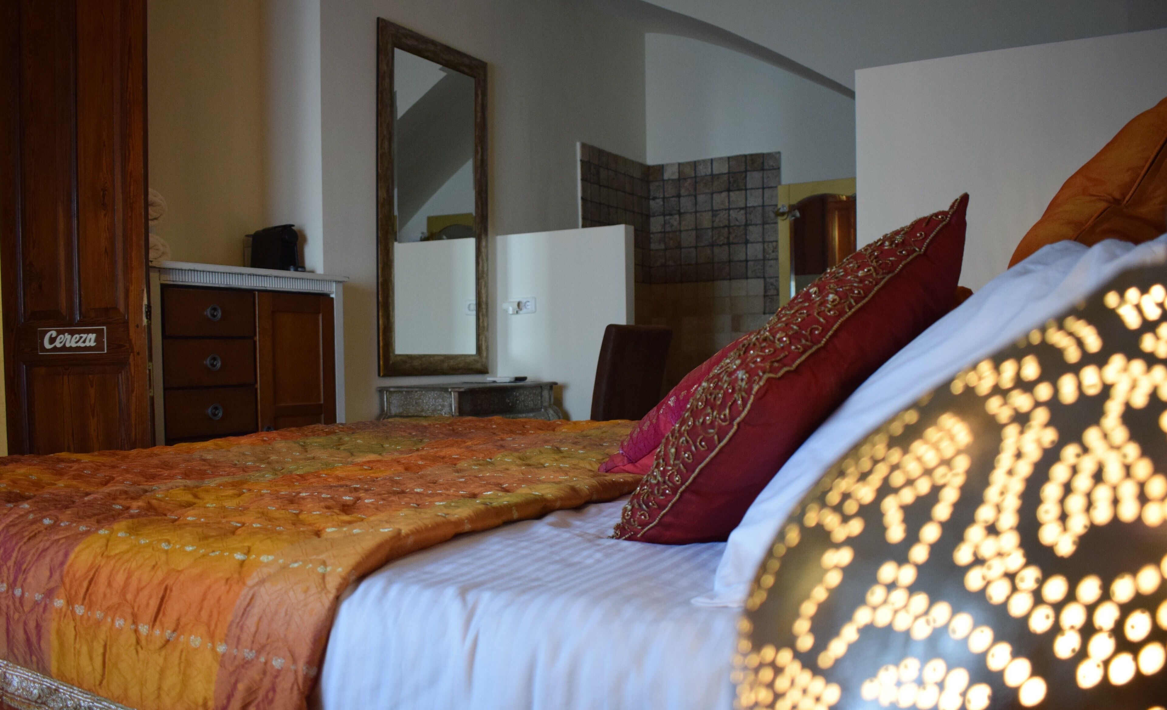 A bedroom with a bed, a dresser, a mirror, and a tiled wall.