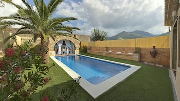 Relax in a serene backyard with a swimming pool, lawn, and mountain views.
