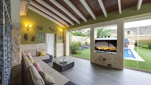 A spacious patio with a sofa, coffee table, and a view of a swimming pool and garden. - Casa Mistela (Jalon)