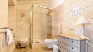 Un baño con ducha de vidrio, inodoro, lavabo y tocador con cajones.