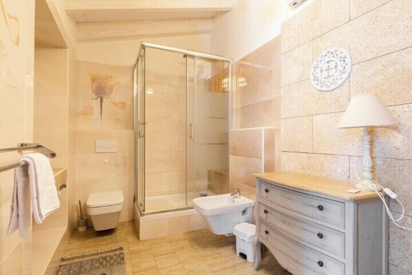 Un baño con ducha de vidrio, inodoro, lavabo y tocador con cajones.