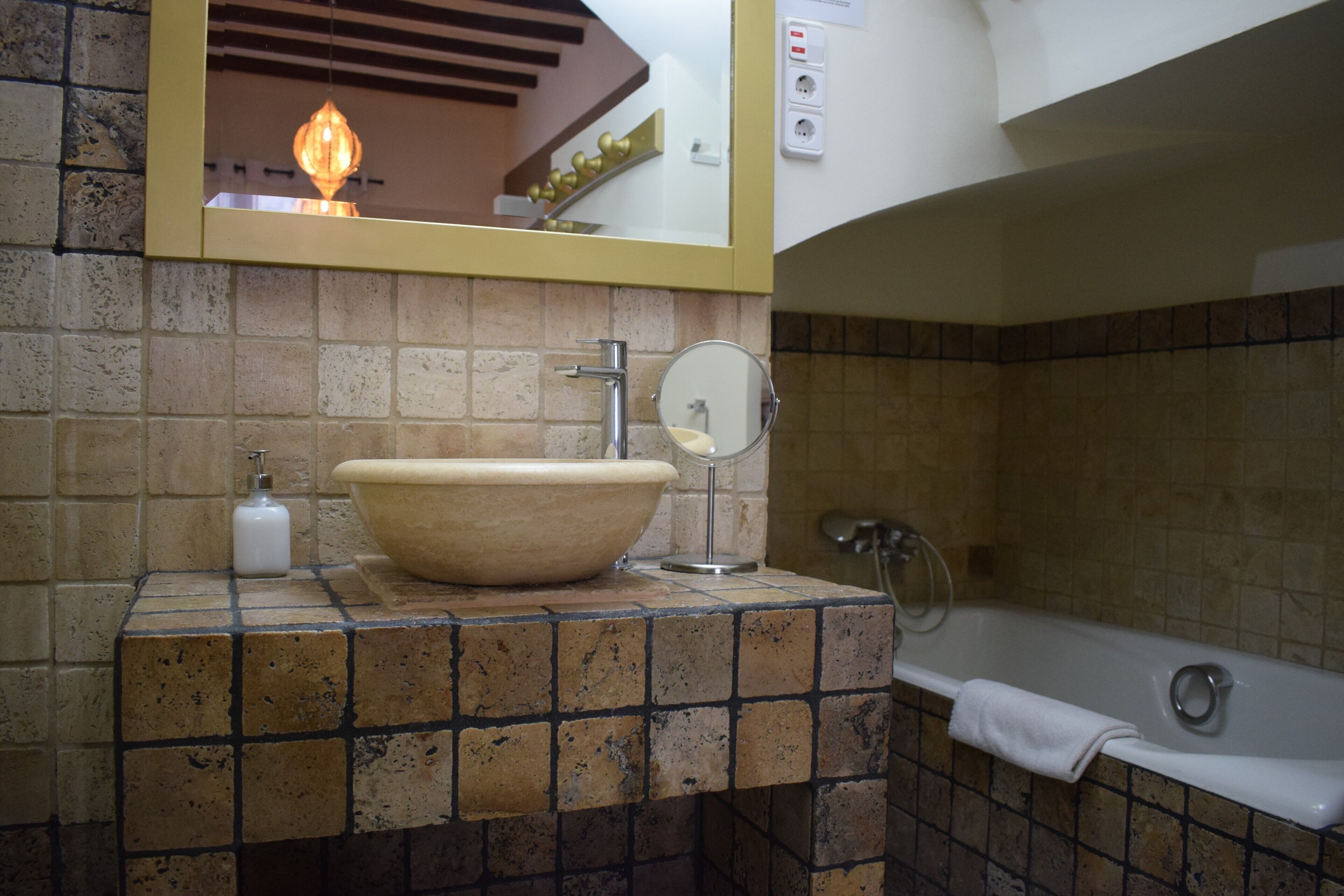 Un baño con un lavamanos grande color beige, un espejo, una toalla y una bañera.