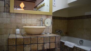 Un baño con un lavamanos grande color beige, un espejo, una toalla y una bañera.
