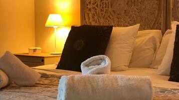 Un lit bien fait, avec des draps blancs et une serviette enroulée posée sur le lit.