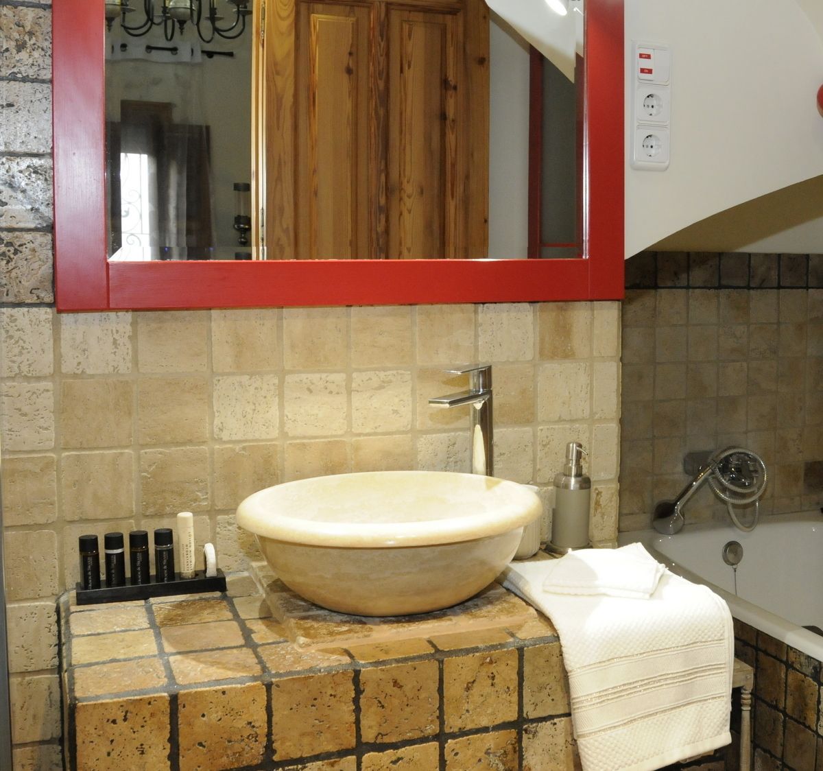 A bathroom with a large, round sink, a mirror above it, and a towel rack.