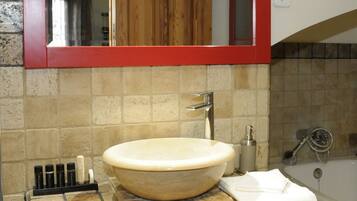 A bathroom with a large, round sink, a mirror above it, and a towel rack.