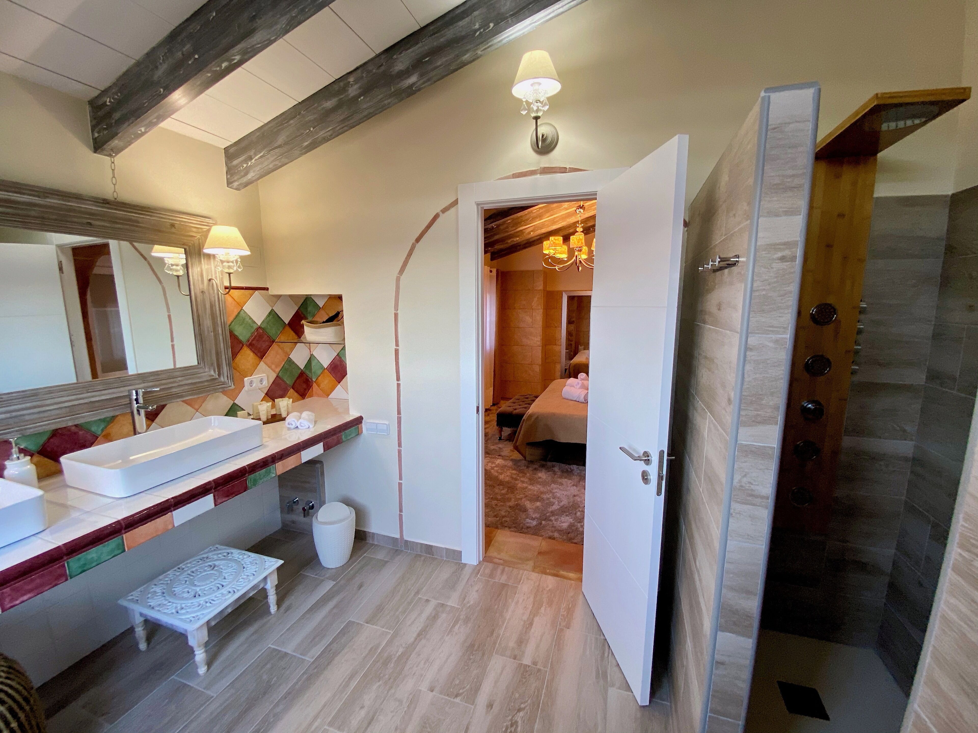 Een moderne badkamer met een grote spiegel, een rechthoekig wastafelmeubel en een bankje.