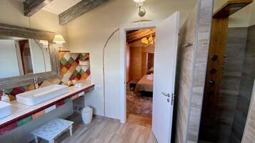 Een moderne badkamer met een grote spiegel, een rechthoekig wastafelmeubel en een bankje.