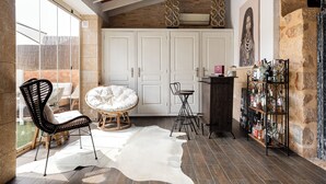A spacious room with a large window, a wicker chair, a round table, a white cowhide rug, and a bar area with bottles. - Casa Mistela (Jalon)