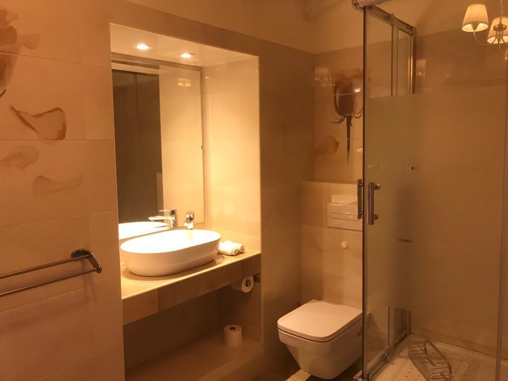 Een moderne badkamer met een douchecabine van glas, een witte wastafel en een toilet.