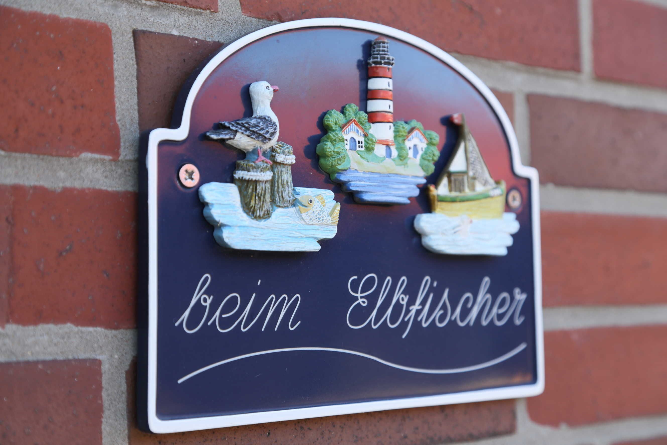 A decorative sign with a bird, lighthouse, and boats, and the text "bei Ellfischer".