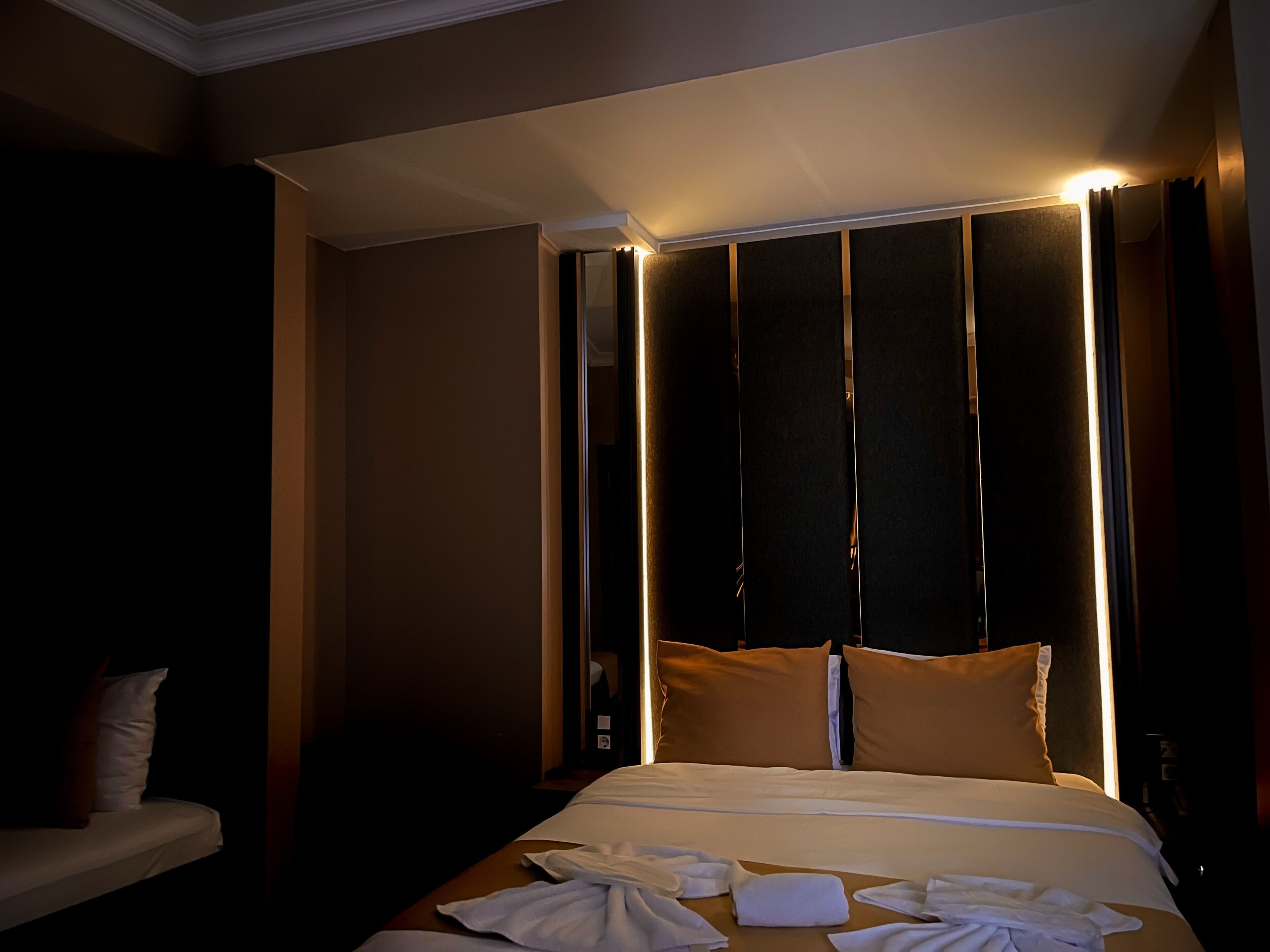 Una habitación de hotel con una cama grande, una mesita de noche y un velador.