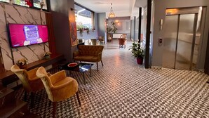 A modern hotel lobby with a patterned floor, comfortable seating, a television, and a view of the city through large windows. - New Taksim  (Istanbul)