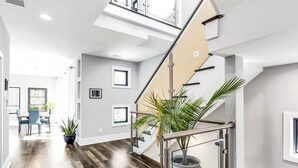 Een modern interieur met een trap, houten vloeren en een eethoek met stoelen en een tafel.