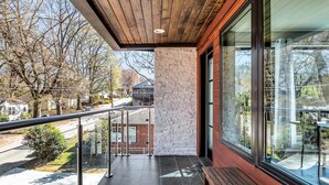 Een modern gebouw met een houten plafond, een glazen wand en een balkon met een metalen hekwerk.