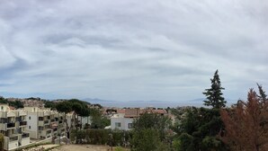 A residential area with modern apartment buildings, a hilly landscape, and a distant view of the sea. - Babylon Gardens Apart Hotel (Menderes)