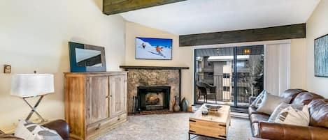 A cozy living room with a fireplace, leather sofas, and a television.