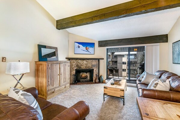 A cozy living room with a fireplace, leather sofas, and a television.