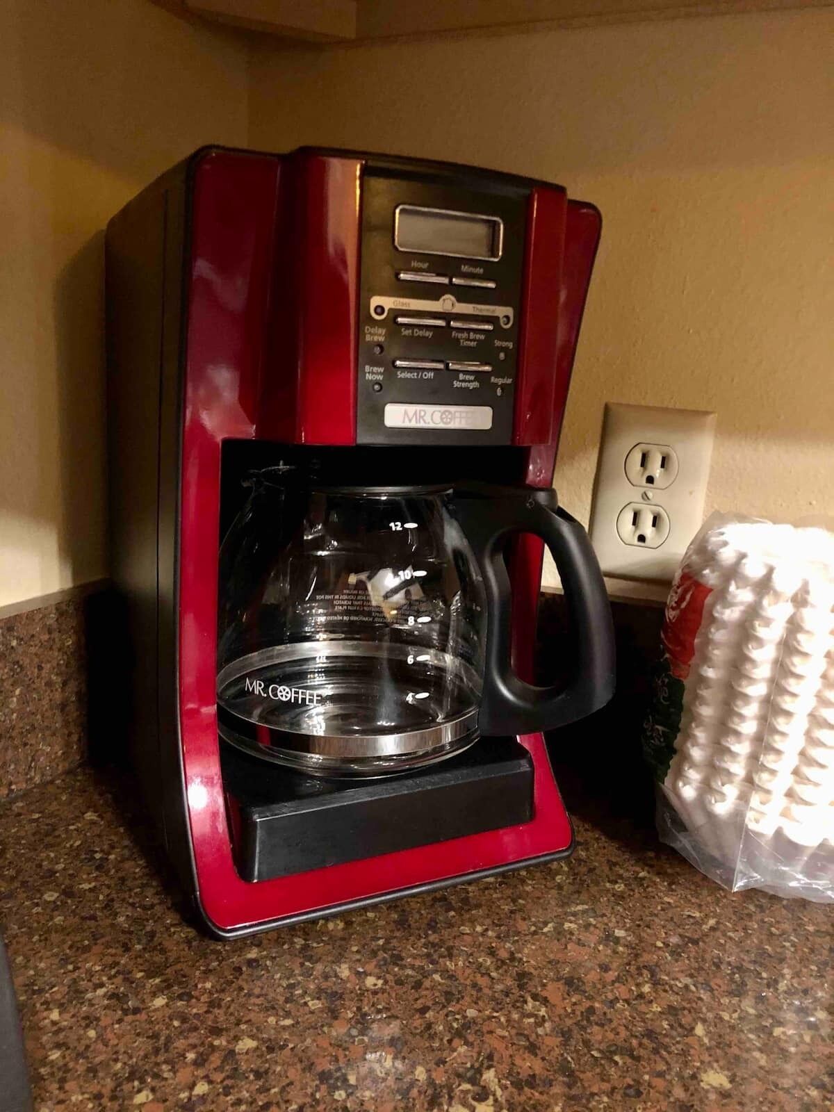 Punainen Mr. Coffee -kahvinkeitin, jossa on lasinen kahvikannu, ja se on sijoitettu graniittitasolle.