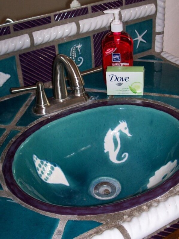 Un lavabo de salle de bain agrémenté d’un pare-éclaboussures décoratif en carreaux, d’un robinet et d’un distributeur de savon.