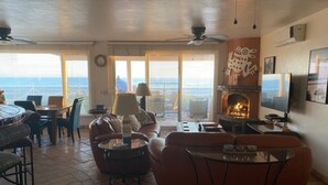 Un salon doté d’une cheminée, d’un coin salon et offrant une vue sur l’océan.