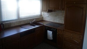A kitchen with wooden cabinets, a sink, a stove, and a dishwasher.