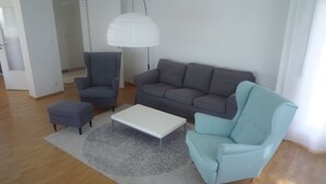 A modern living room with a grey sofa, a blue armchair, a white coffee table, and a grey rug.