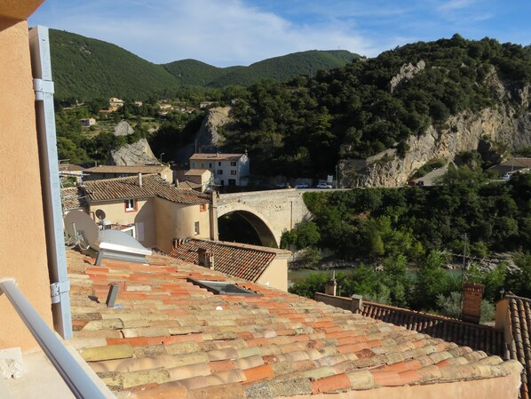 A terracotta-tiled roof, a stone bridge, and a mountainous landscape with buildings.