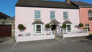 A pink building with three windows and a small porch area. - Old Temperance House (Helston)