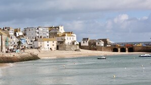 A coastal town with historic buildings, a sandy beach, and boats in the water. - Old Temperance House (Helston)
