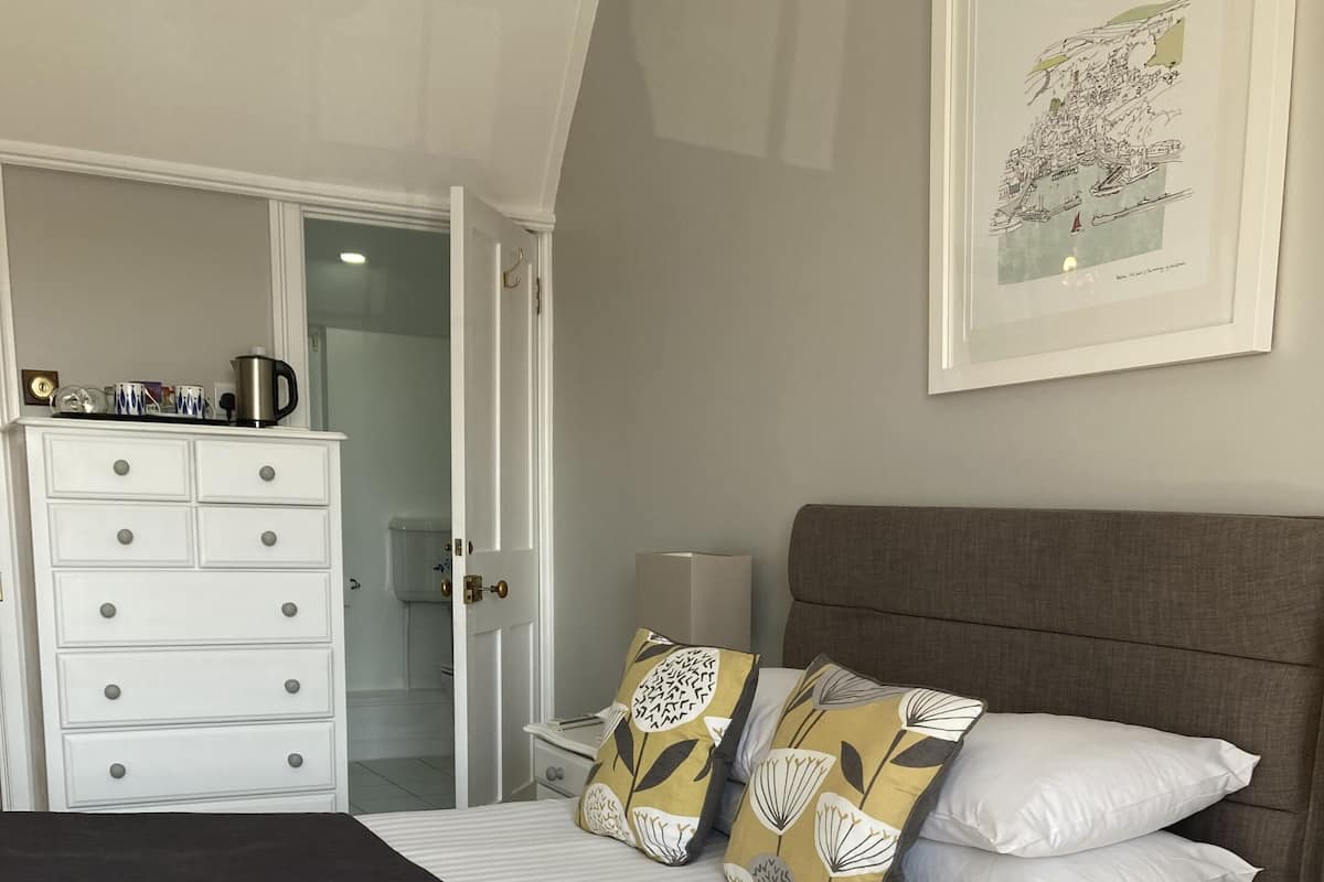 A bedroom with a bed, a dresser, a nightstand, and a framed picture on the wall.