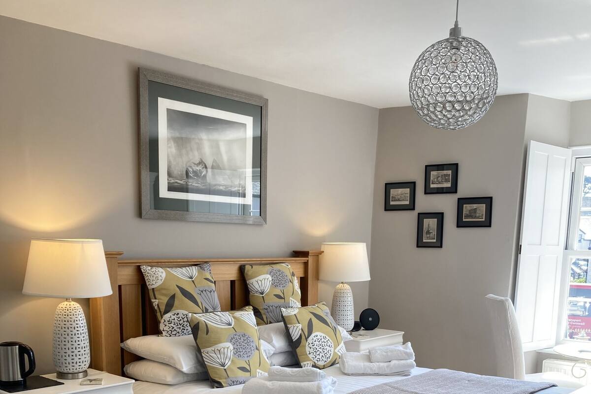 A neatly arranged bedroom with a wooden bed, white nightstands, and a hanging light fixture.