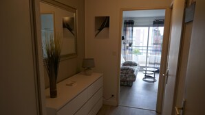 A hotel room with a white dresser, a mirror, a vase, and a lamp. There is a door leading to a balcony with a view of the outside. - New in Pornic T2 terrace SO view golf parking all on foot (Pornic)