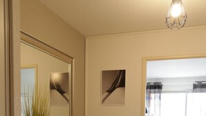 A modern bathroom with a white vanity, a mirror, a vase with green plants, and a bedside table with a lamp. - New in Pornic T2 terrace SO view golf parking all on foot (Pornic)
