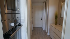 A narrow hallway with a wooden floor, a white door at the end, and a small plant on a white console table. - New in Pornic T2 terrace SO view golf parking all on foot (Pornic)