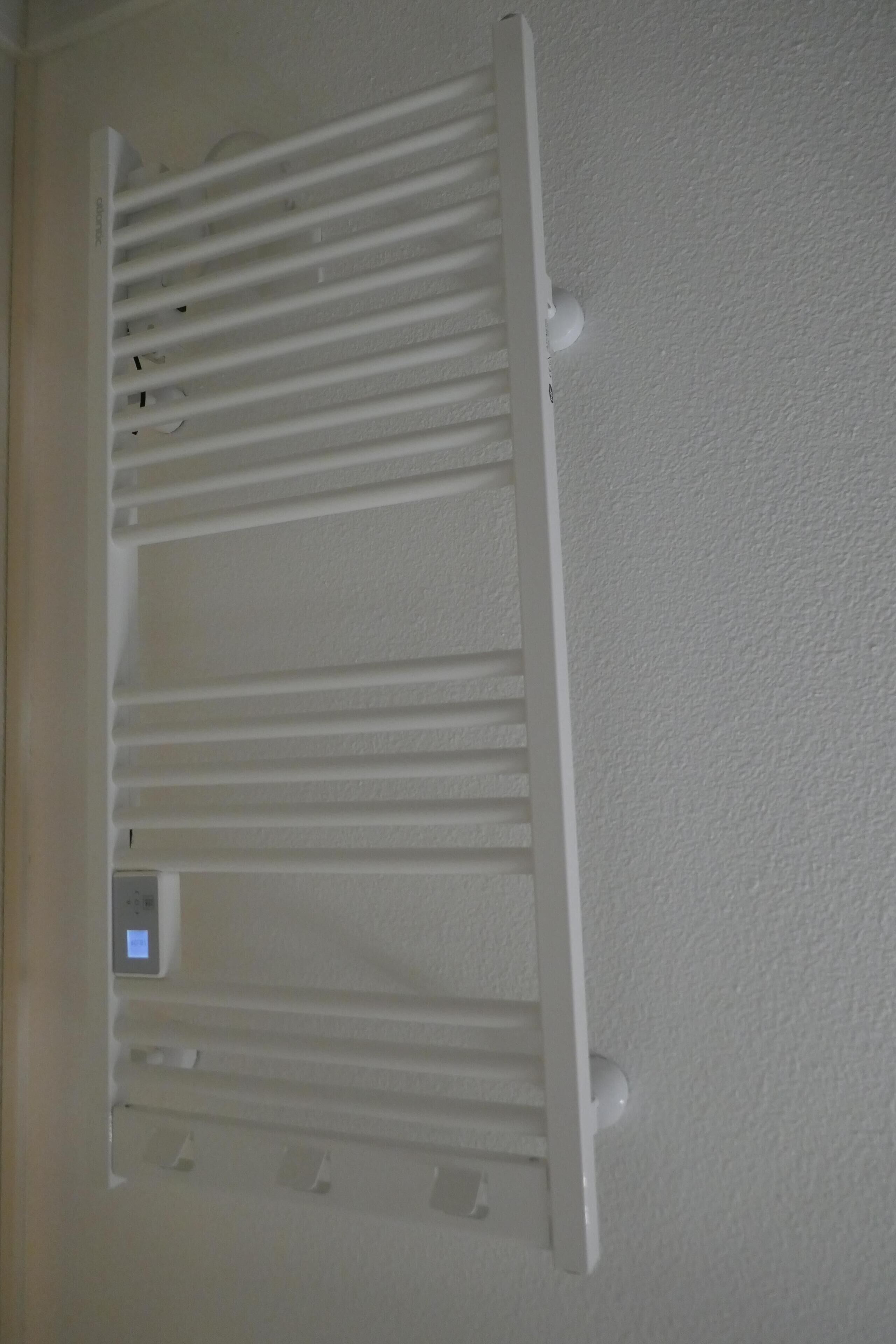 A white wall-mounted radiator with a digital control panel.