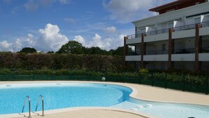 A swimming pool with a clear blue sky and a building with a balcony in the background. - New in Pornic T2 terrace SO view golf parking all on foot (Pornic)