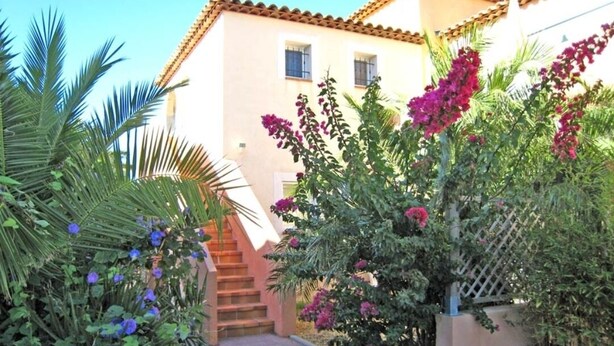 A building with a tiled roof, a staircase, and various plants including bougainvillea and palm trees. - Studio 25 M2, air-conditioned 350mt from the beach. (Hyères)