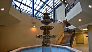 Eine mehrstufige Fontäne in einem großzügigen Atrium mit hoher Decke und Dachfenstern.