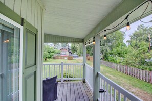Eine überdachte Veranda mit weißem Geländer, eine Sitzecke mit Kissen und Lichterketten.