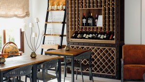 A dining area with a wooden table and chairs, a wine rack with bottles, and a globe on a shelf. - Casa Rural Canelobre (Busot)