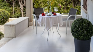 Un patio al aire libre con una mesa redonda preparada para comer, rodeada de sillas.
