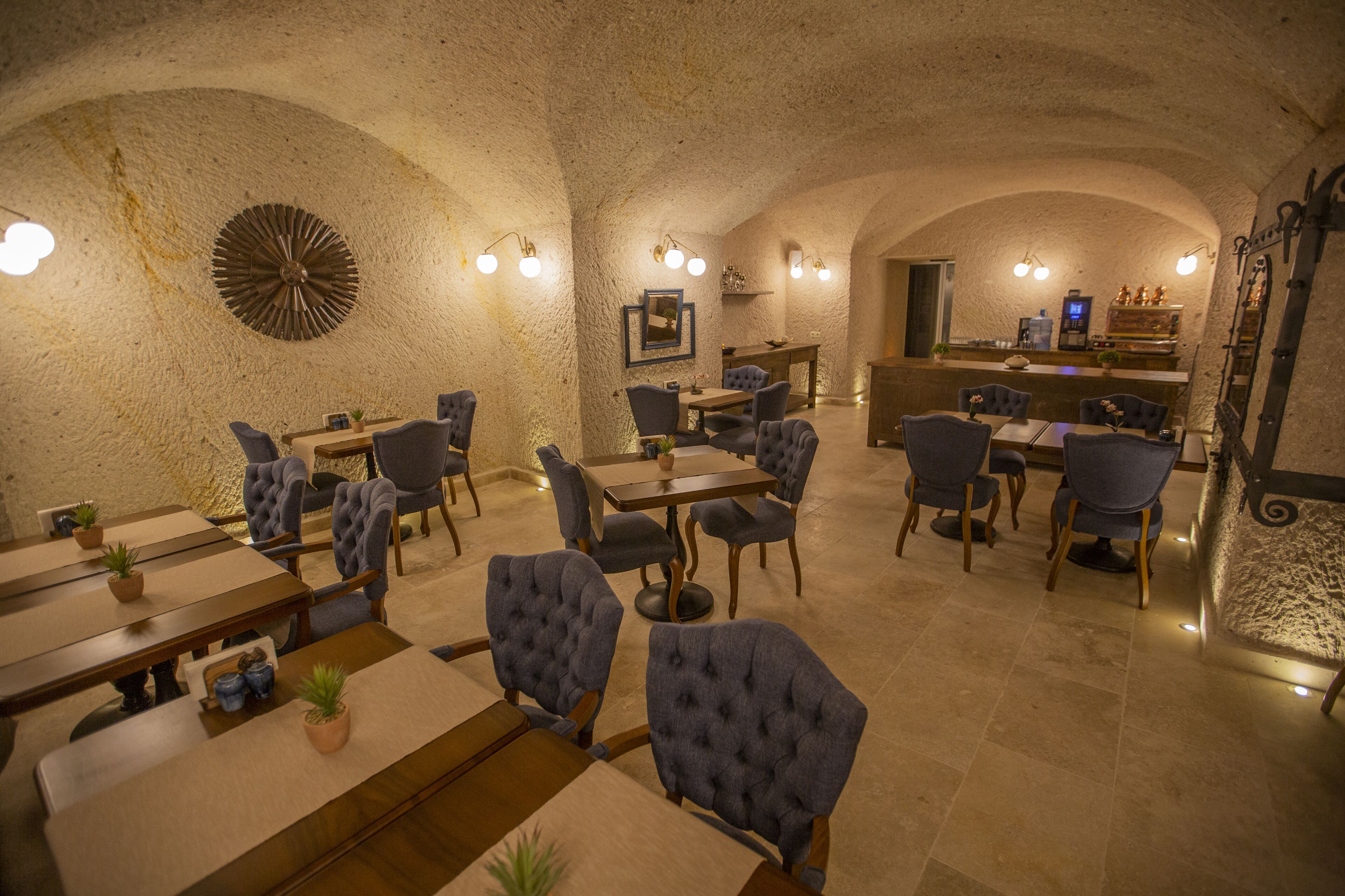 A restaurant with stone walls, round tables, and blue upholstered chairs.