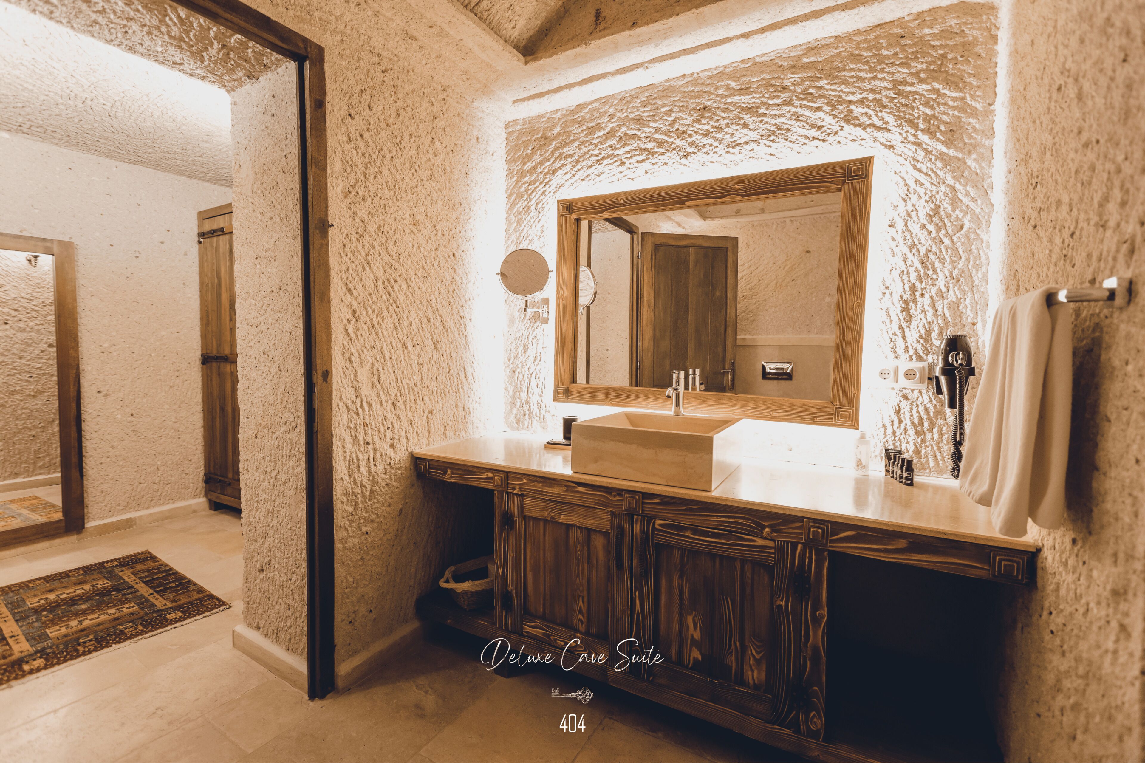 A bathroom with a stone wall, wooden vanity, and a large mirror.