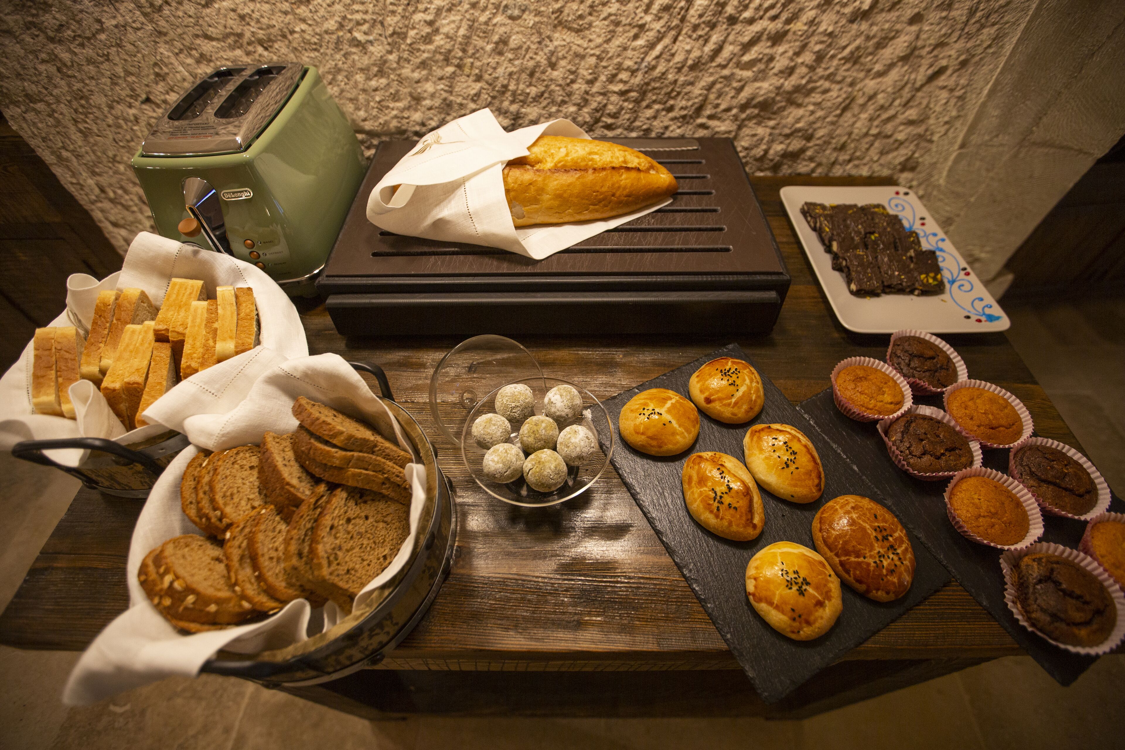 Diverse gebakken producten, zoals brood, muffins en gebak, op een houten tafel.