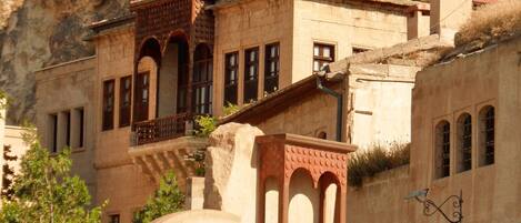 Un bâtiment à la façade en pierre et aux fenêtres en arc de cercle, sur lequel on peut voir une enseigne avec les inscriptions « ASMAKI KOMAK » et « ANS INTERNATIONAL PRODUCTIONS ».