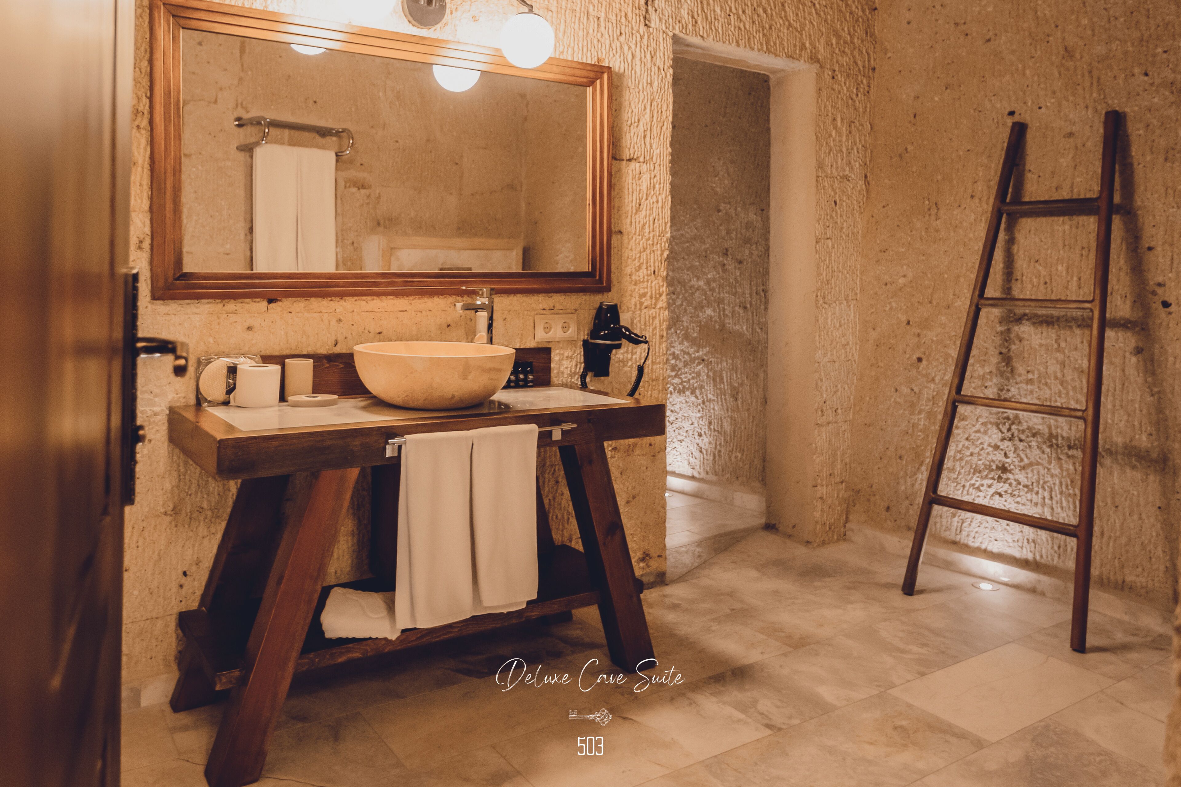 A bathroom with a large mirror, a wooden vanity, a bowl sink, and a towel rack.